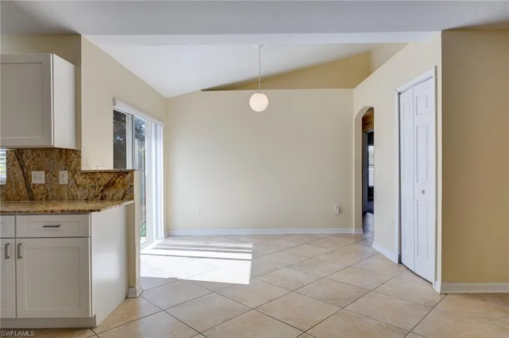 Unfurnished dining area featuring lofted ceiling, arched walkways, healthy amount of natural light, and light tile patterned flooring
