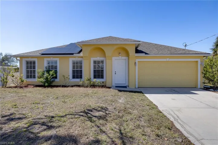 View of front of home with roof with shingles, stucco siding, roof mounted solar panels, a garage, and concrete driveway