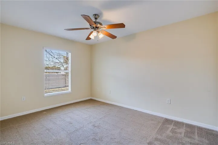 Unfurnished room with light colored carpet and a ceiling fan