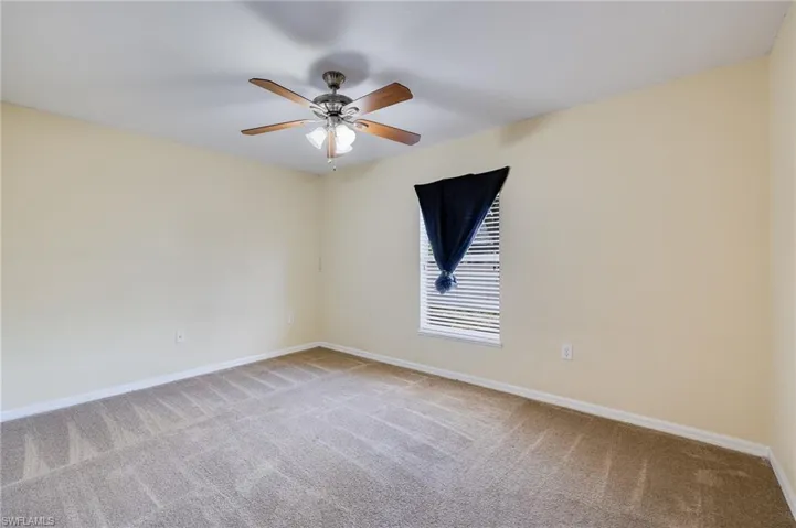 Empty room featuring light carpet and a ceiling fan
