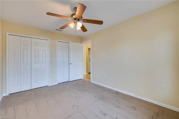Unfurnished bedroom with multiple closets, carpet flooring, and ceiling fan