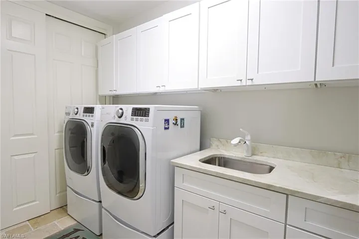 Laundry area featuring sink, cabinets, washer and dryer, and light tile patterned floors