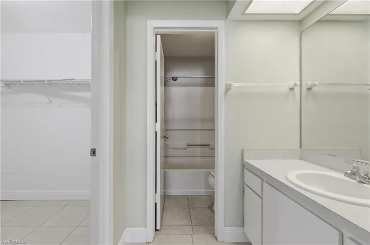 Bathroom vanity with an integrated sink, polished chrome faucet, and expansive wall mirror