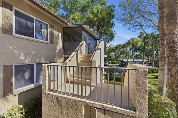 Exterior featuring a textured stucco finish, multiple windows, decorative shutters, and an external staircase leading to an upper-level screened enclosure