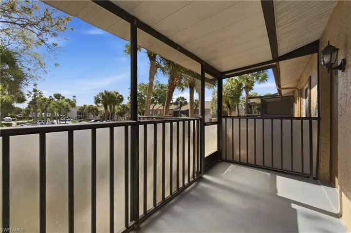 Screened balcony featuring a textured ceiling, exterior wall-mounted light fixture, and a durable floor finish
