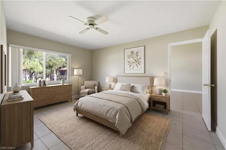 Spacious room featuring light-toned tile flooring, a large window with white blinds, neutral wall paint, and a ceiling fan with light fixture