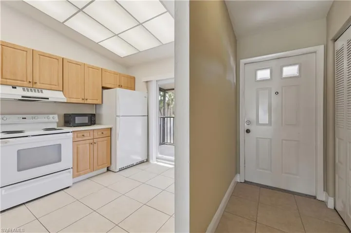 Kitchen area featuring wood-finish cabinetry, white appliances, and tiled flooring