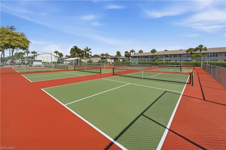 Multiple outdoor pickleball courts featuring green playing surfaces and red surrounds