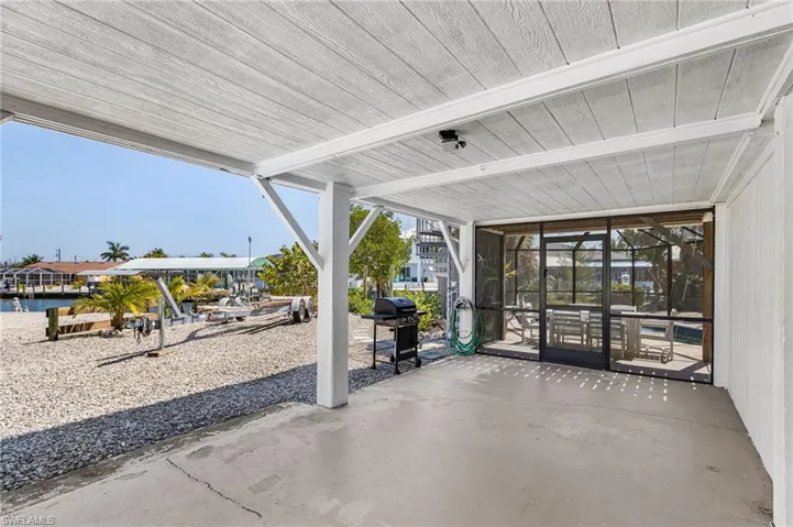 Open carport with entrance to the pool and storage shed.