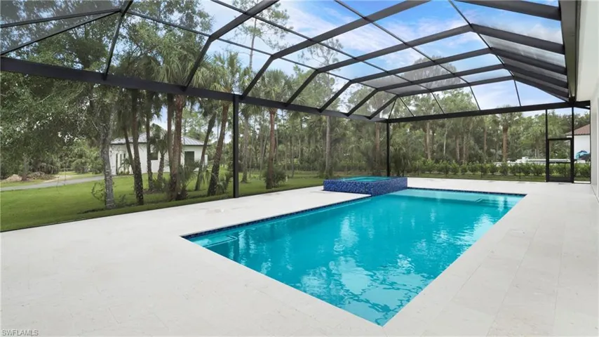 View of swimming pool with a yard, glass enclosure, a patio, a pool with connected hot tub, and a sunroom