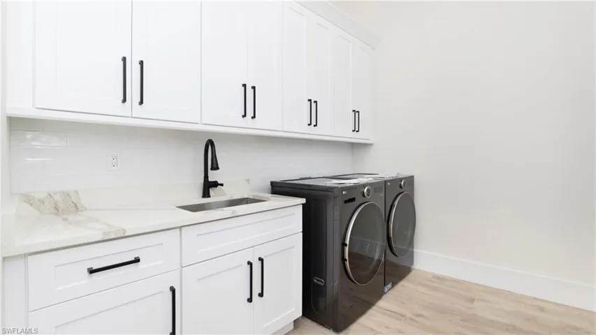 Laundry area with light wood-style floors, independent washer and dryer, and cabinet space