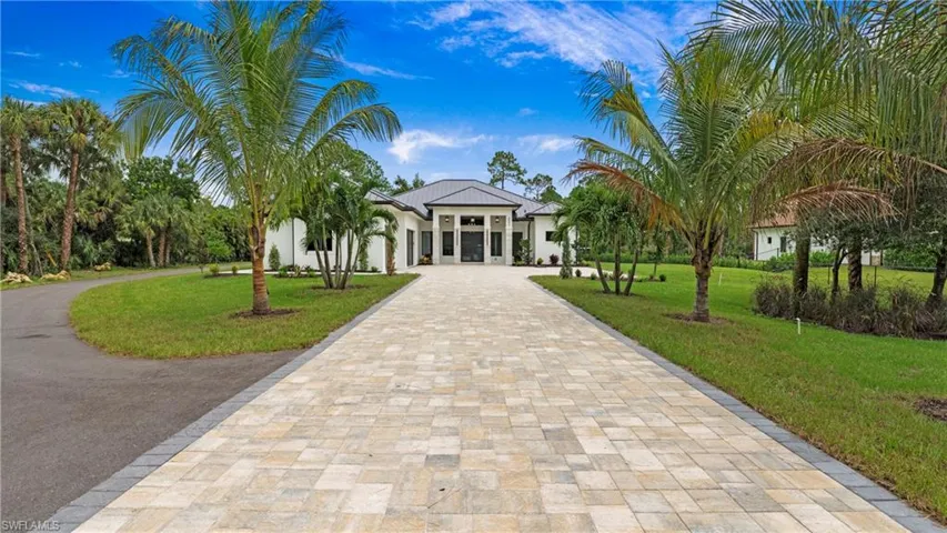 View of property's community with curved driveway, a lawn, and a sunroom