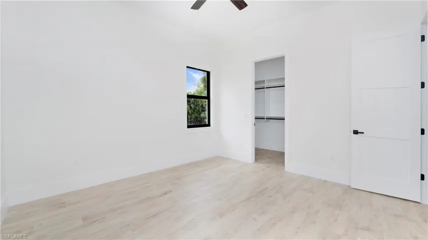 Unfurnished bedroom featuring a spacious closet, light wood-type flooring, and ceiling fan