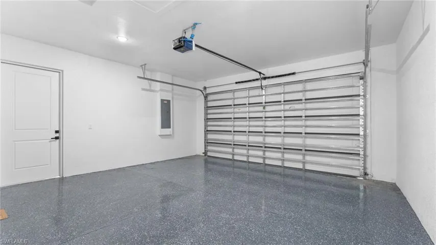 Garage featuring electric panel and a garage door opener
