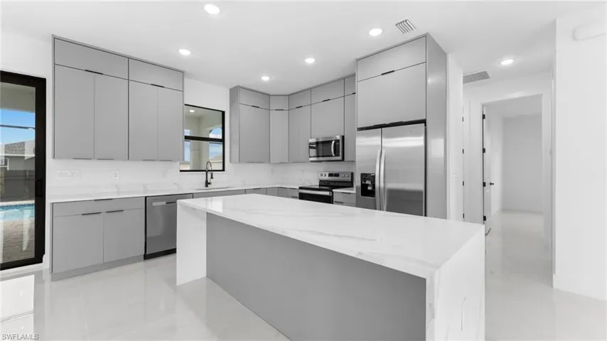 Kitchen featuring gray cabinetry, sink, a kitchen island, and appliances with stainless steel finishes