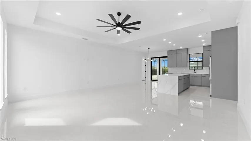 Unfurnished living room featuring a tray ceiling and ceiling fan