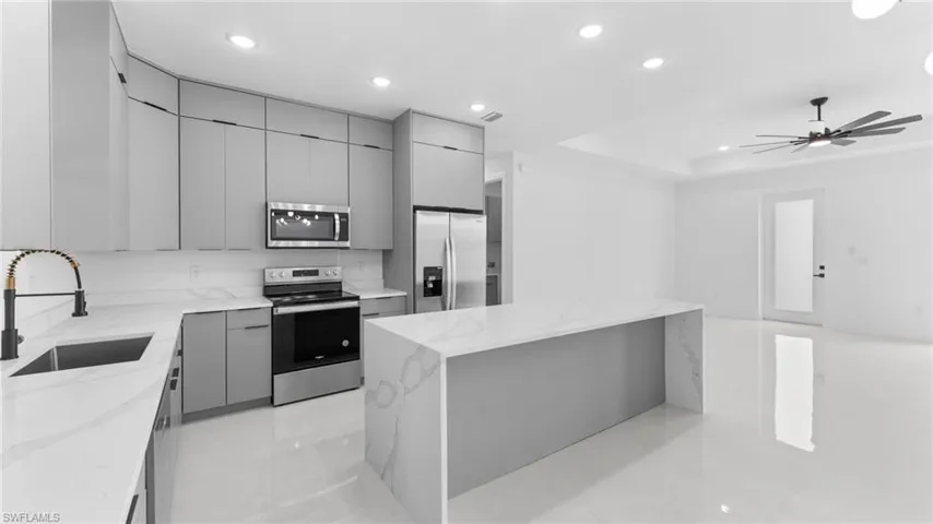 Kitchen with gray cabinets, sink, a center island, and stainless steel appliances