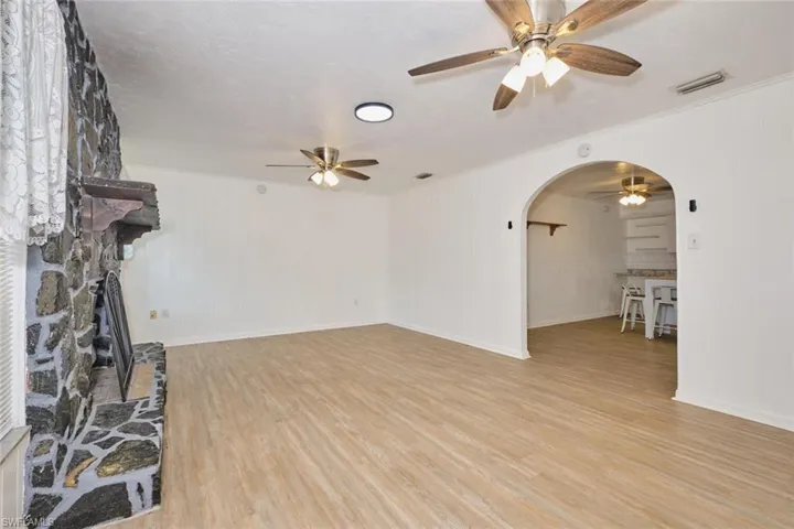 Unfurnished living room with a stone fireplace, ceiling fan, and light hardwood / wood-style flooring