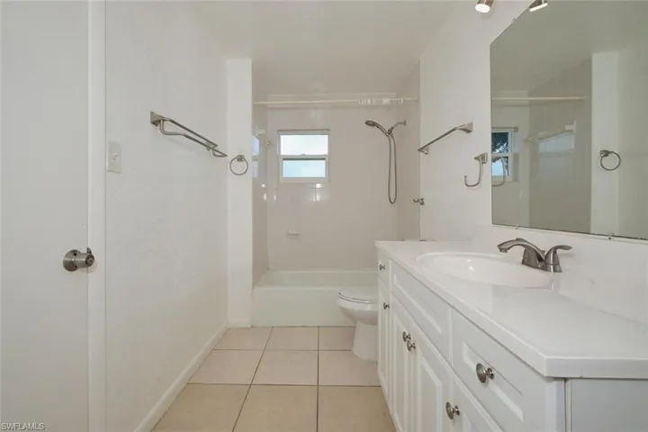 Full bathroom with tile patterned floors, tiled shower / bath combo, vanity, and toilet
