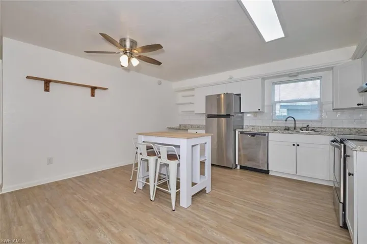Kitchen with ceiling fan, white cabinets, sink, light hardwood / wood-style flooring, and stainless steel appliances