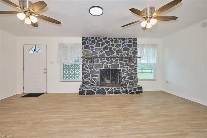 Living room with ceiling fan, a fireplace, and light hardwood / wood-style flooring