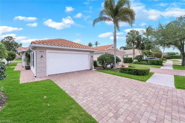 Mediterranean / spanish-style home with a front lawn, a tiled roof, a garage, stucco siding, and decorative driveway