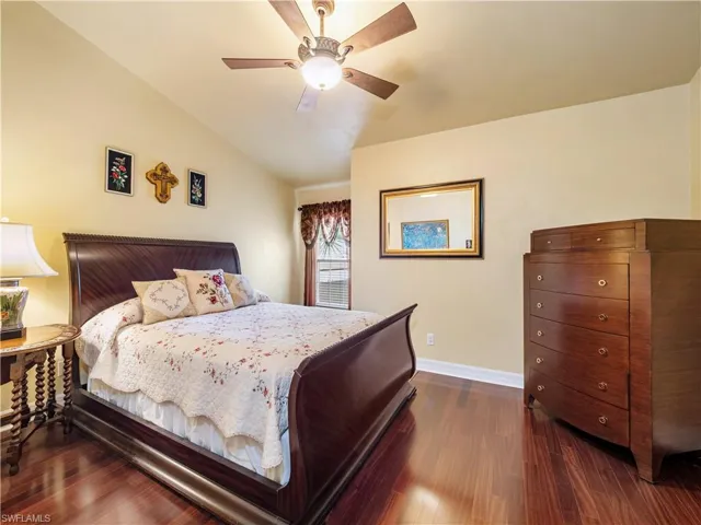 Bedroom with dark wood-style flooring, a ceiling fan, and vaulted ceiling