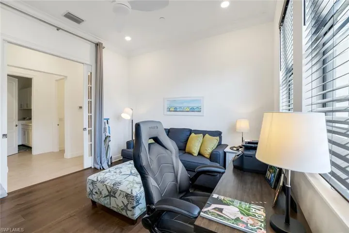 Living area featuring dark wood-style floors, crown molding, and recessed lighting