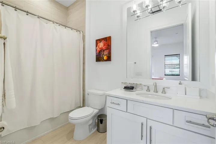 Bathroom with vanity, light wood finished floors, shower / bath combo, and a chandelier