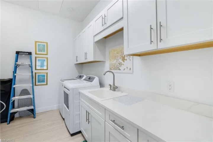 Laundry room with washing machine and dryer, cabinet space, and light wood-style floors