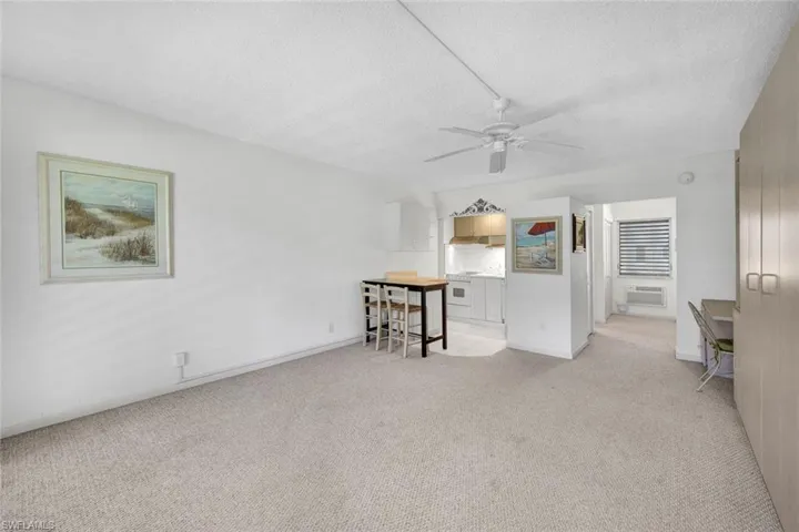 Unfurnished living room with light carpet, an AC wall unit, ceiling fan, and a textured ceiling