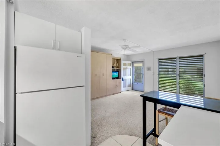 Kitchen with light carpet, a textured ceiling, white fridge, and ceiling fan