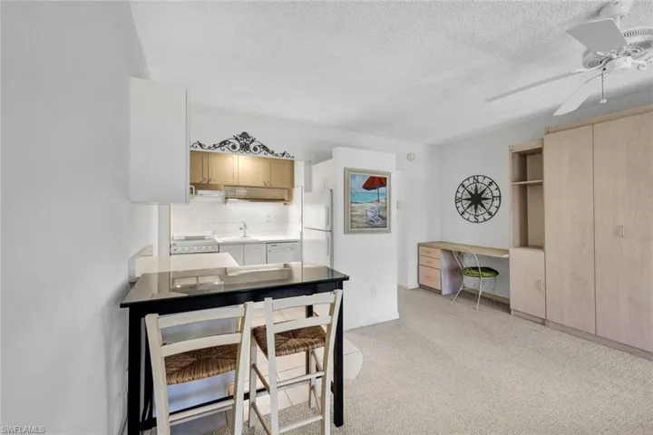 Kitchen with light brown cabinetry, ceiling fan, tasteful backsplash, light carpet, and white appliances