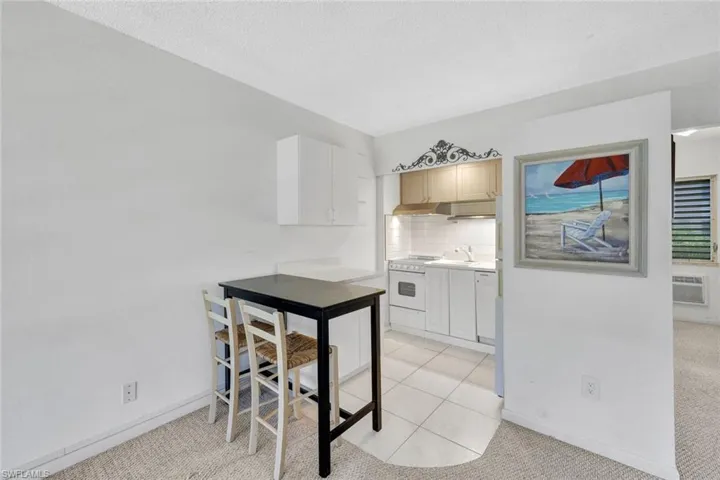 Kitchen featuring a wall mounted AC, electric stove, backsplash, light tile floors, and sink