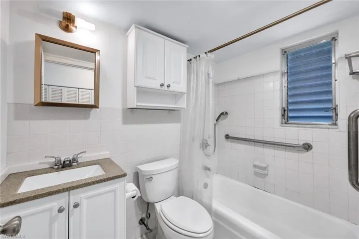 Full bathroom featuring shower / tub combo, tile walls, backsplash, toilet, and vanity