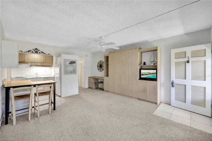 Kitchen featuring a textured ceiling, light carpet, white fridge, ceiling fan, and light brown cabinets