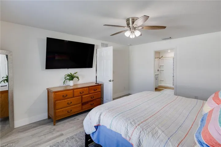 Bedroom with ensuite bath, ceiling fan, and light wood finished floors
