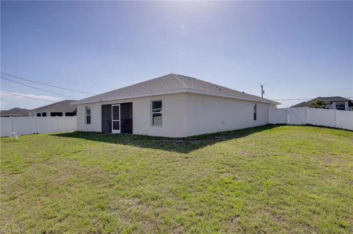 Rear view of house featuring a fenced backyard, stucco siding, a sunroom, and a gate