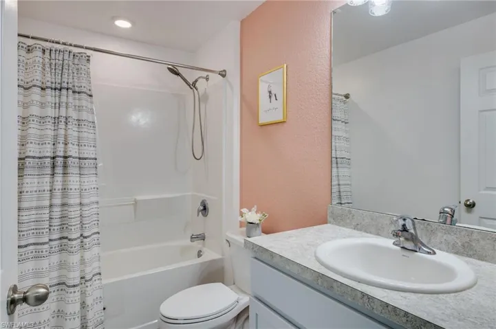 Bathroom featuring a textured wall, vanity, and shower / bath combination with curtain