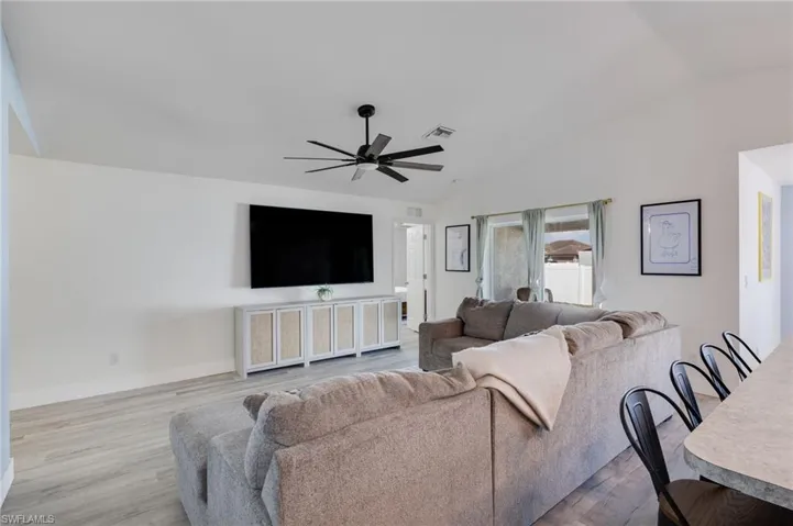 Living room with light wood-style floors, ceiling fan, and lofted ceiling