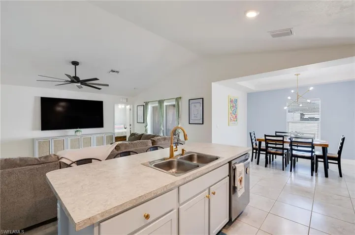 Kitchen featuring open floor plan, a center island with sink, a chandelier, light countertops, and lofted ceiling