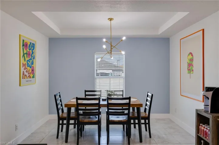 Dining space featuring a tray ceiling, hanging lights, and light tile patterned floors