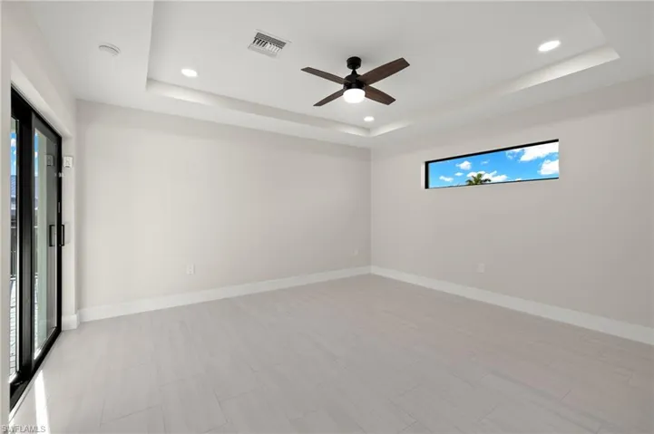 Unfurnished room featuring light tile patterned floors, ceiling fan, and a raised ceiling
