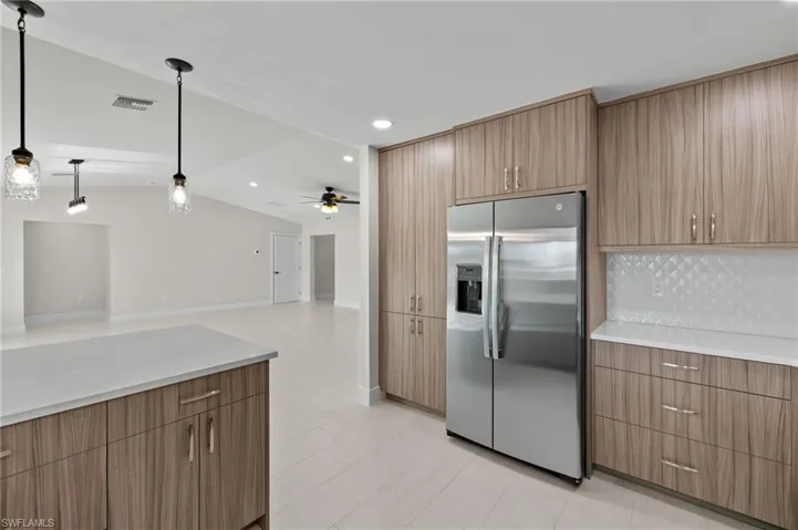 Kitchen with light tile patterned flooring, ceiling fan, high end refrigerator, decorative backsplash, and decorative light fixtures