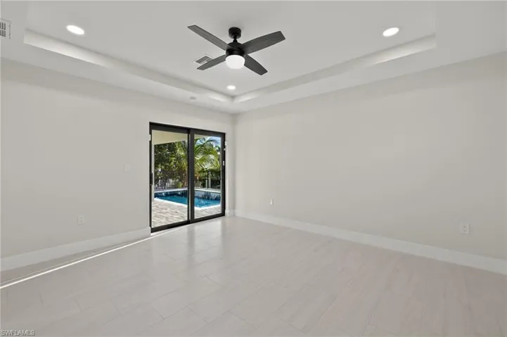 Spare room featuring light tile patterned flooring, ceiling fan, and a tray ceiling