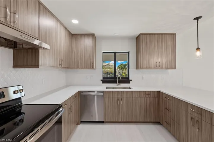 Kitchen with decorative light fixtures, decorative backsplash, sink, appliances with stainless steel finishes, and light tile patterned floors