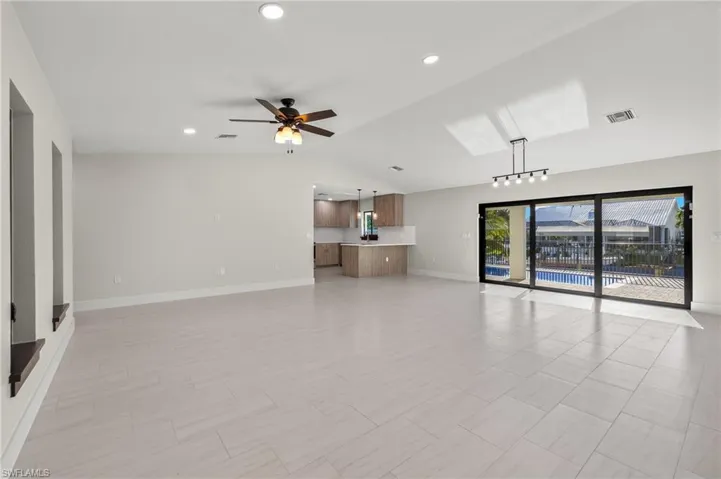 Unfurnished living room featuring light tile patterned flooring, rail lighting, ceiling fan, and lofted ceiling