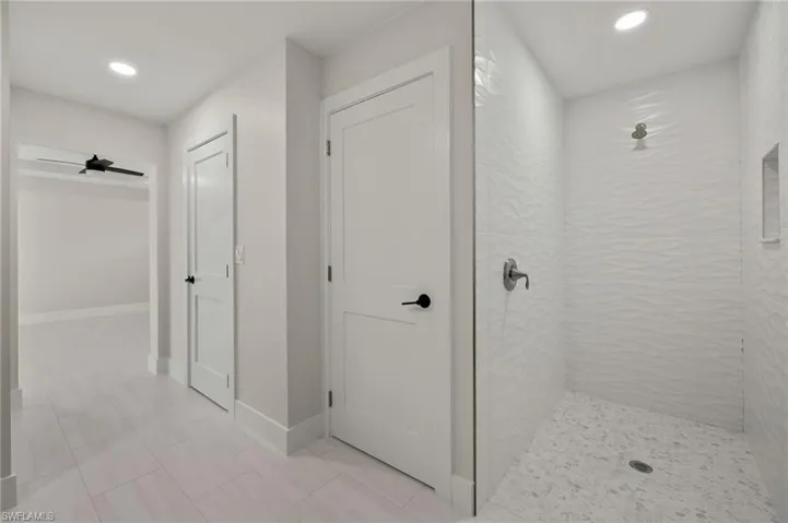 Bathroom with tiled shower, tile patterned floors, and ceiling fan