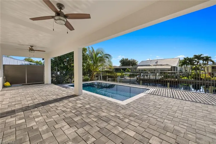 View of swimming pool with a patio, a water view, and ceiling fan