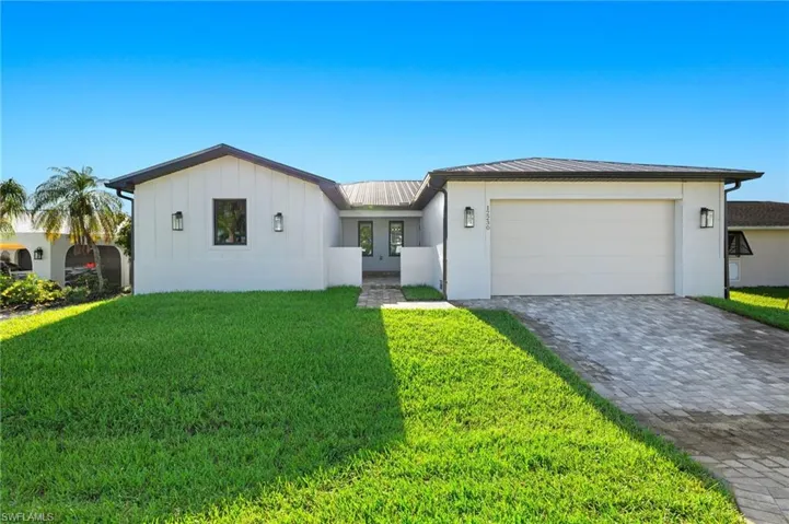 View of front of property with a garage and a front lawn